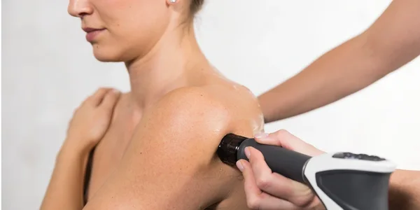 Person receiving shoulder treatment with a device.