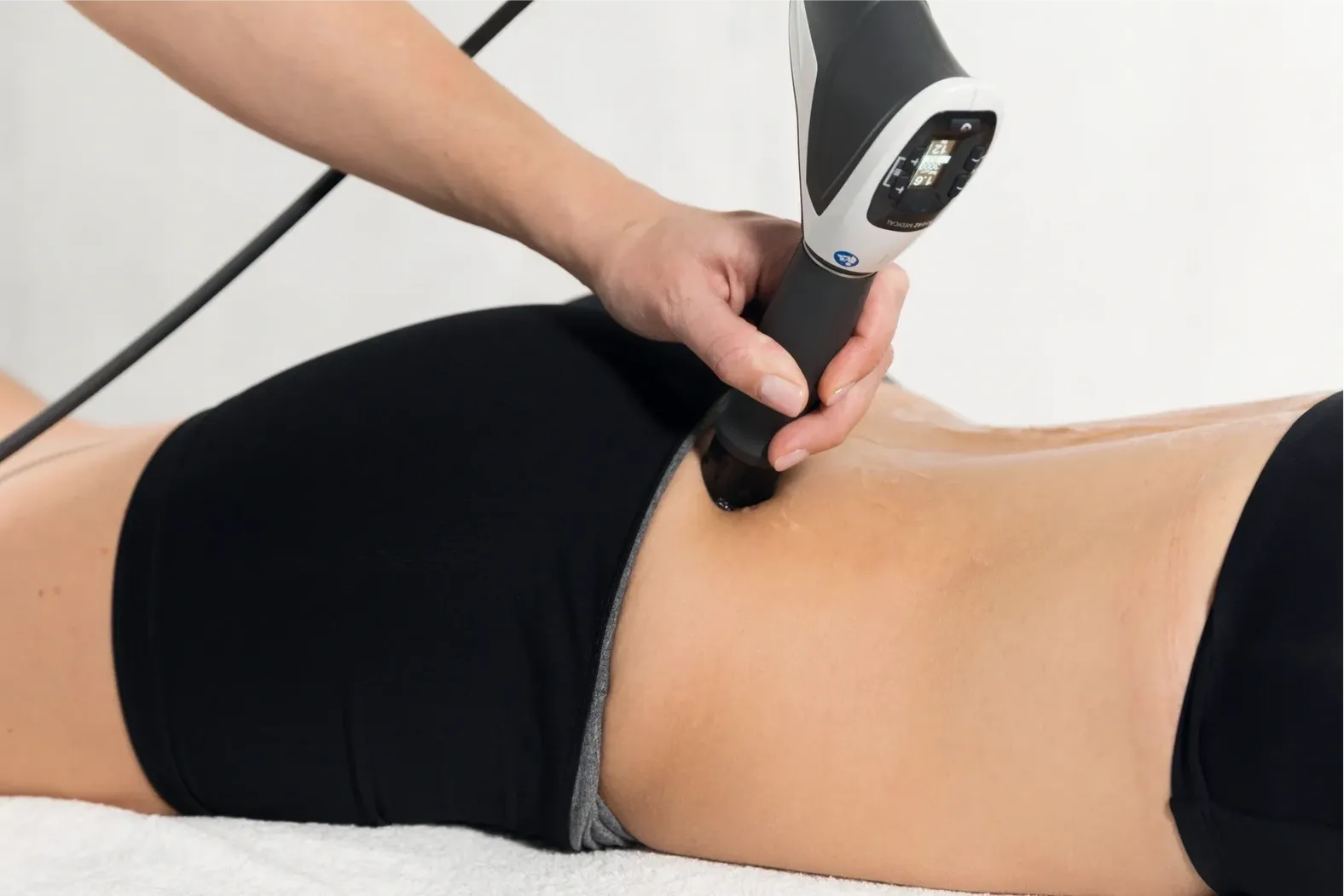 Person receiving non-invasive body contouring treatment.
