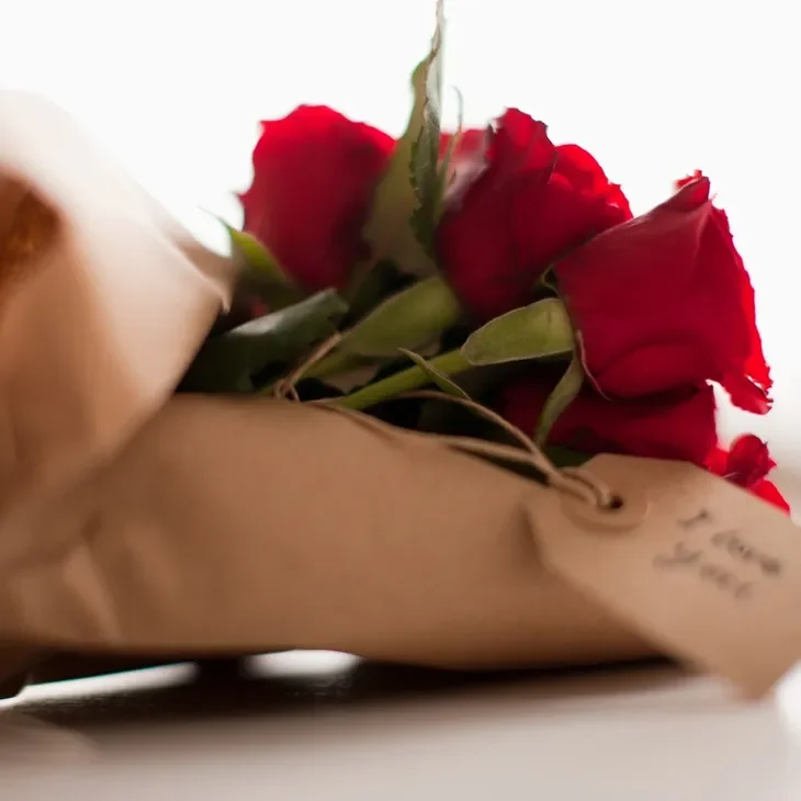 Bouquet of red roses wrapped in paper.